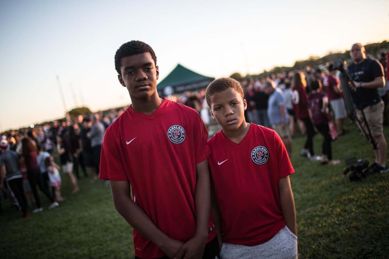 Jonathan Hines, de 13 años, y Jacob Hines, 9, posan con sus camisetas del equipo de fútbol de la escuela. "Llevar esta camiseta hoy significa mucho porque ayuda a recordar a los que murieron", explica Jonathan. Una de las 17 víctimas mortales del tiroteo jugaba fútbol con ellos. Un rato antes de la vigilia Jonathan y Jacob se reunieron con decenas de los jugadores de fútbol de la escuela para recibir un discurso del entrenador. "Intenten mantener los recuerdos y mantenerse positivos", recuerda Jonathan que les dijo.