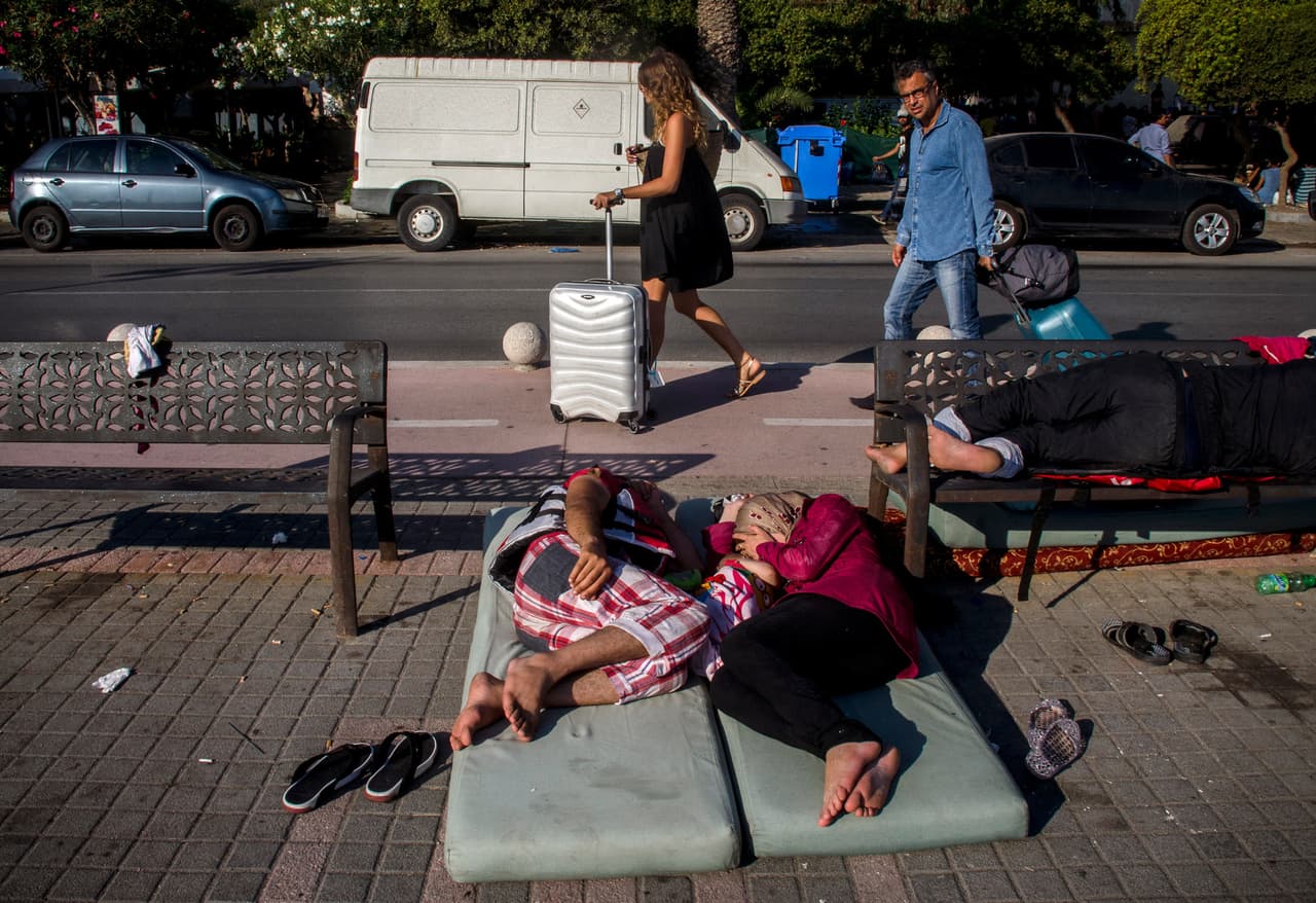 <b>Capítulo 2. “No hay cielo ni tierra cuando te hundes en el mar”. </b>El mundo de los turistas y de los refugiados apenas coincide en el tiempo y en los lugares. La mayoría de los botes desembarcan al amanecer cuando los turistas todavía duermen en sus hoteles y los refugiados duermen en la calle, lo más cerca posible de la comisaría. Suelen coincidir en el puerto del ferry, pero los oficiales de la Autoridad Portuaria desalojan a gritos y con porra en mano a los que osan dormir en la zona o intentar fotografiar la escena
<b><a href="http://huelladigital.univisionnoticias.com/crisis-refugiados-javier-bauluz/capitulo-2/">(VER ESPECIAL COMPLETO).</a></b>