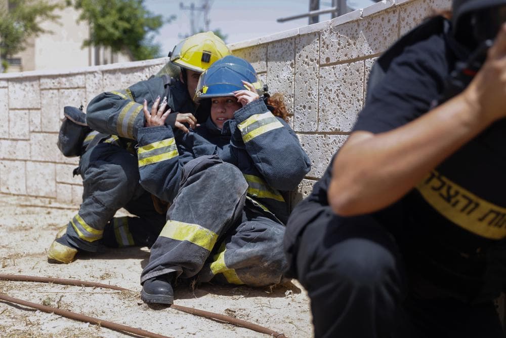 Bomberos israelíes intentan cubrirse al oír las sirenas que anuncian cohetes en la ciudad de Ashkelon, en el sureste de Israel. Este martes cayó una lluvia de cohetes sobre áreas palestinas en la Franja de Gaza y el sur de Israel y ayer Hamas ya lanzó más de 100 cohetes contra Jerusalén.