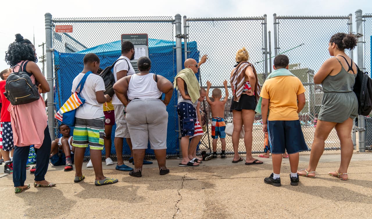 Familias hacen fila para entrar a una piscina pública.