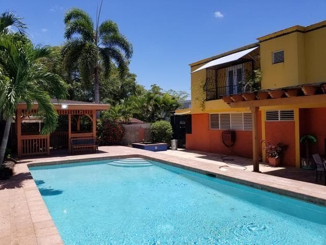 En la parte posterior de la casa hay piscina y dos quioscos rodeados de vegetación.