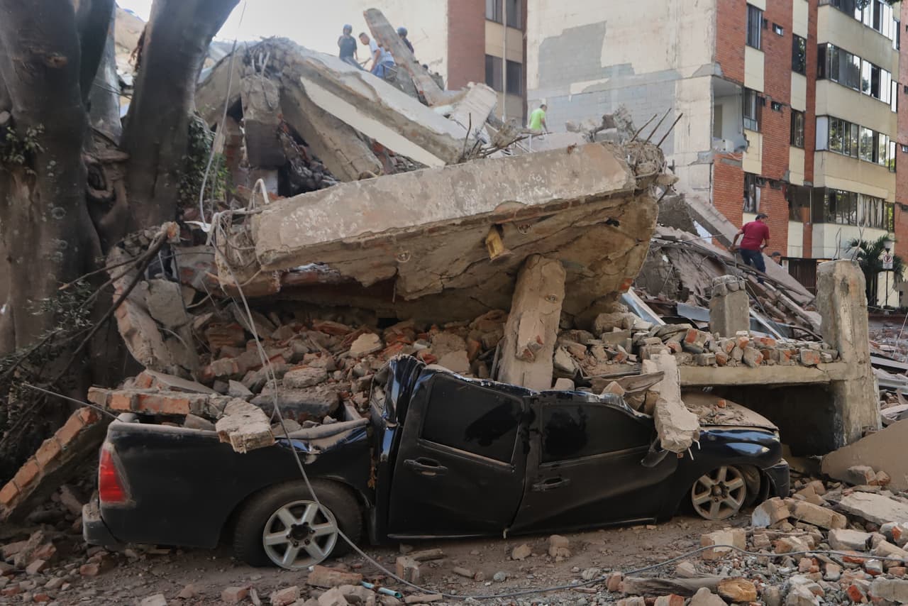 Un vehículo de color negro quedó aplastado bajo los escombros, destrozándolo por completo