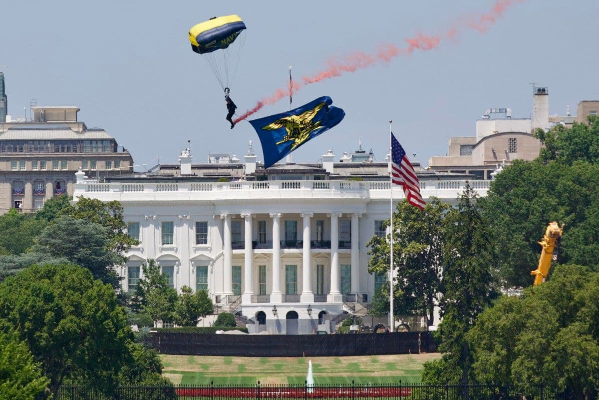 Un miembro del equipo de paracaidistas del Ejército de los Estados Unidos, los "Golden Knights", desciende con una bandera en honor a los prisioneros de guerra y desaparecidos en combate (POW/MIA) estadounidenses sobre el National Mall, cerca de la Casa Blanca, durante la celebración del Día de la Independencia "Salute to America" en Washington, D.C., el 4 de julio de 2026.