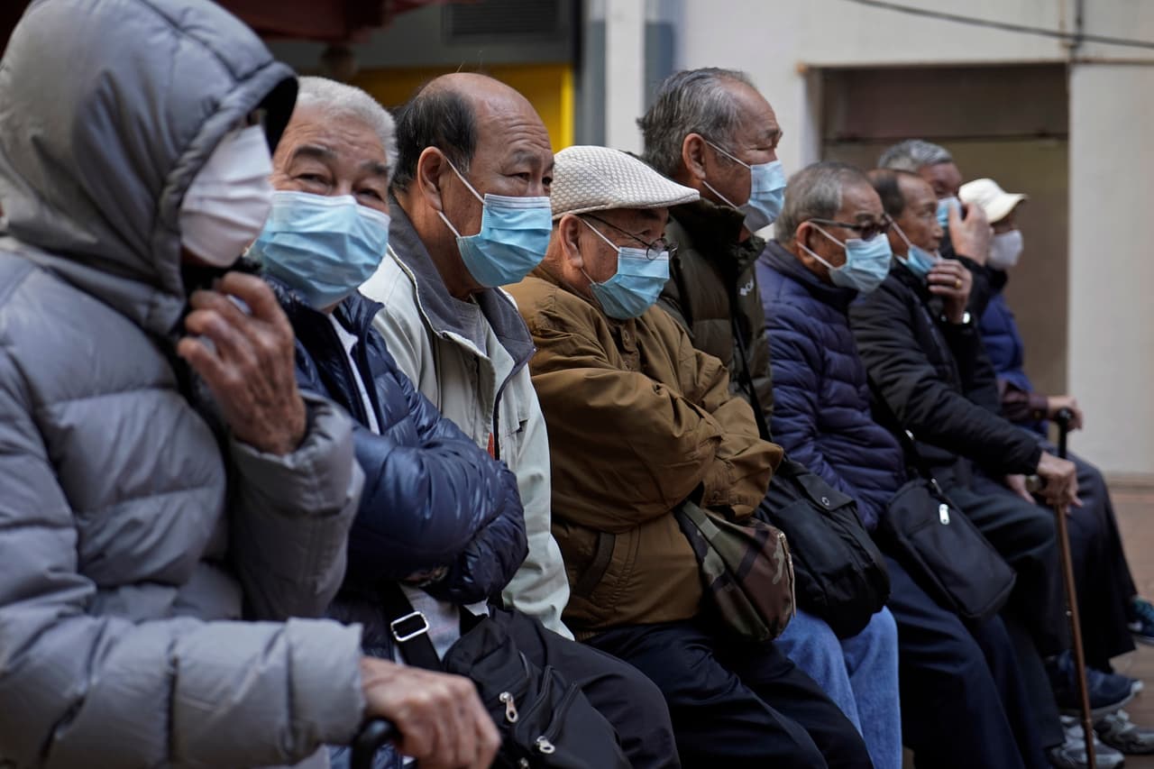 Un grupo de hombres sentados en un parque en Hong Kong este jueves, horas después de que fuera cerrado el servicio de tren hacia y desde China para prevenir una mayor propagación del coronavirus.