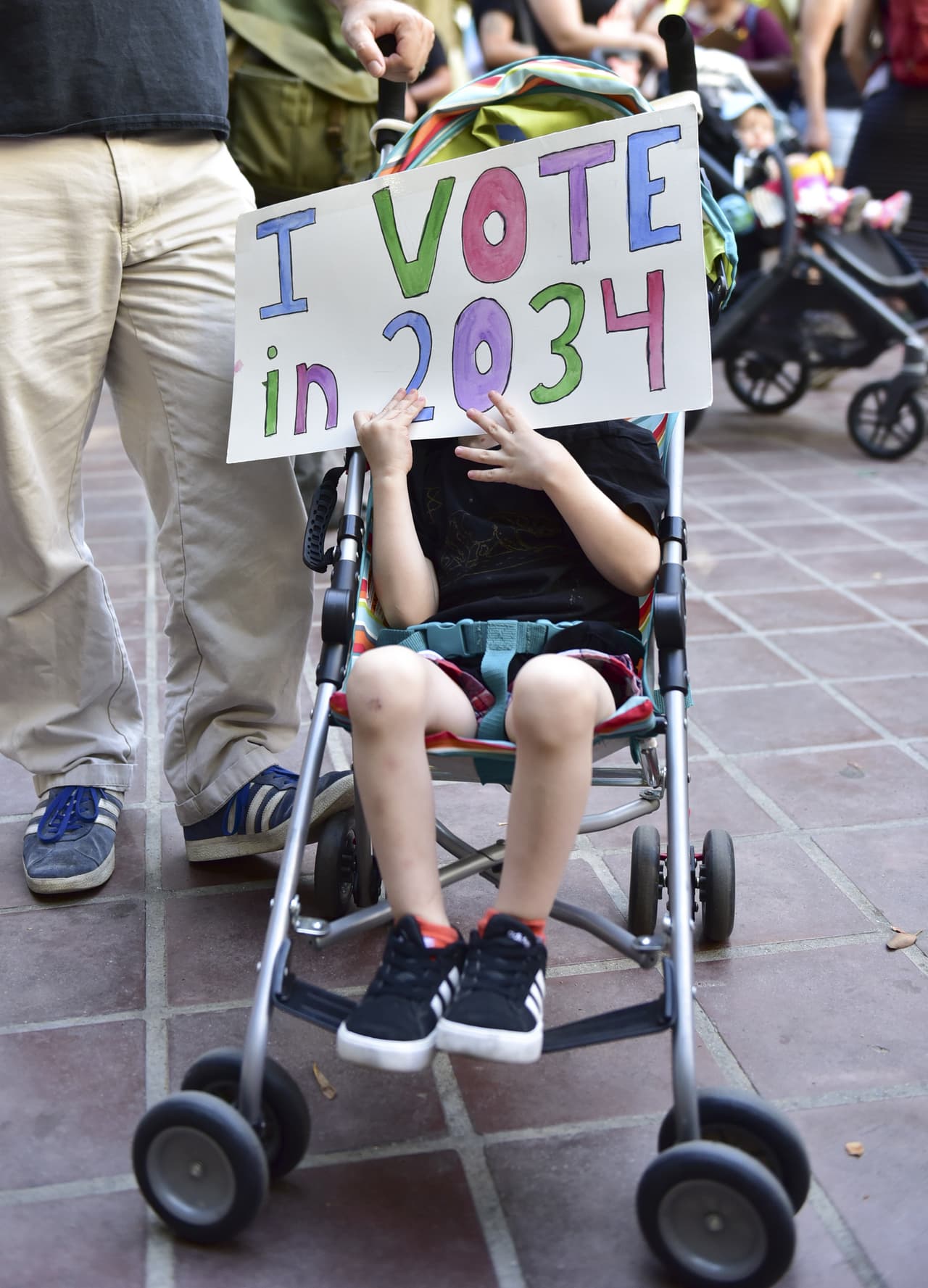 "Yo votaré en 2034", dice el cartel que lleva un niño.