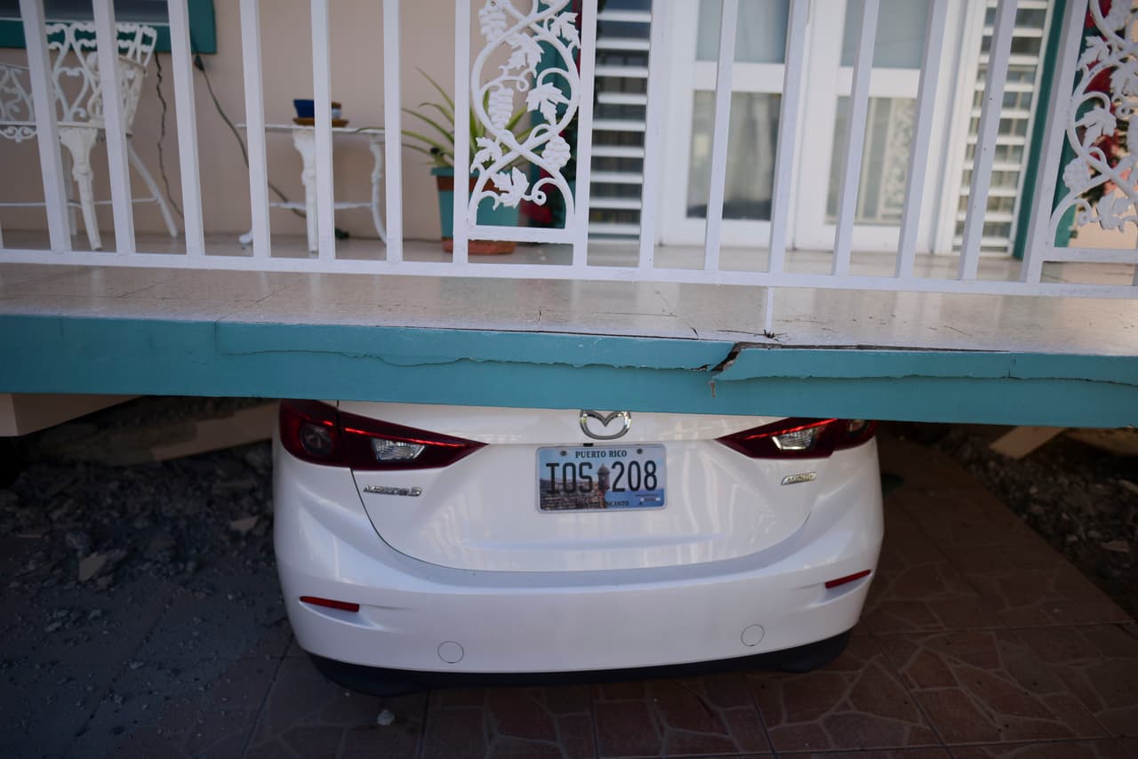 Una casa derrumbada sobre un auto en Guánica. La carretera que une a esta localidad con la capital, San Juan, quedó bloqueada por piedras muy grandes que se derrumbaron sobre la vía con el sismo, según contó un testigo a la agencia AP.