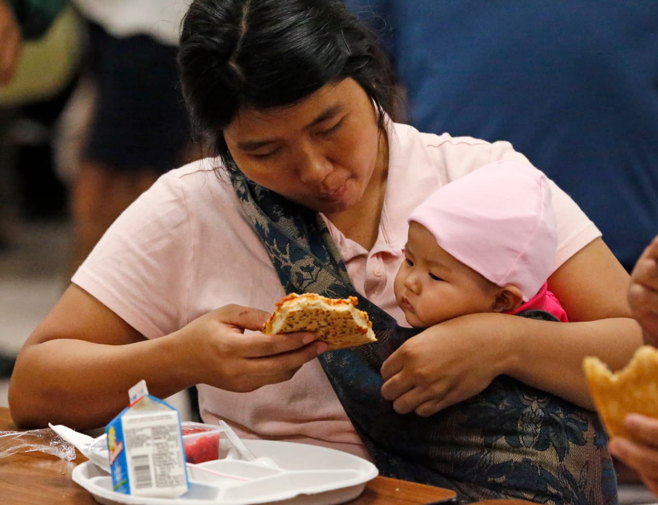 Mang Don Man, of Miami, attends to her seven-month-old baby Vung Vaang Nuam as they eat lunch at a Red Cross shelter set up at North Miami Beach Senior High School, Friday, Sept. 8, 2017 in North Miami Beach, Fla. Cuba evacuated tourists from beachside resorts and Floridians emptied stores of plywood and bottled water after Hurricane Irma left at least 20 people dead and thousands homeless on a devastated string of Caribbean islands and spun toward Florida for what could be a catastrophic blow this weekend. (AP Photo/Wilfredo Lee)