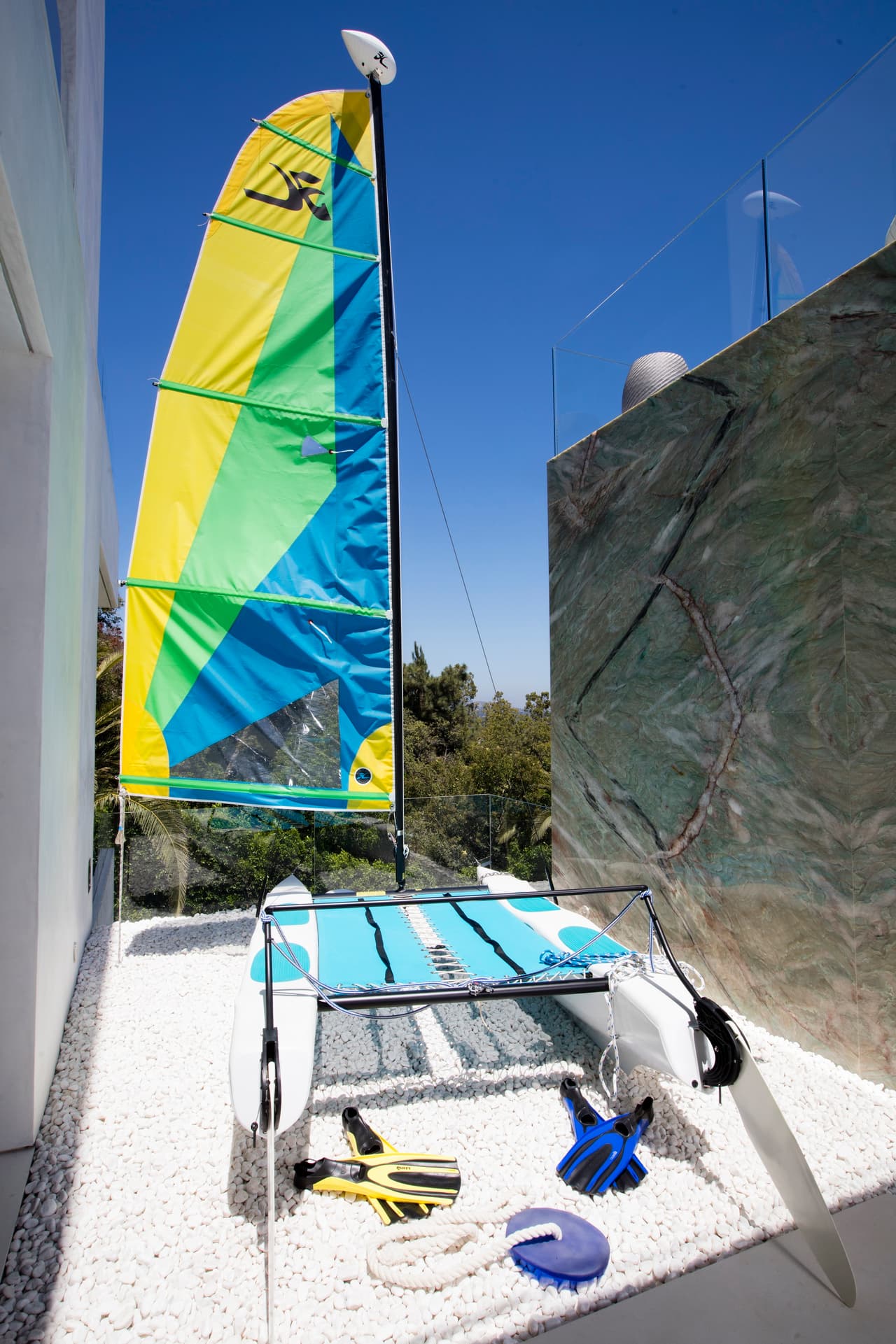 Este pequeño catamarán tipo Hobie Cat está junto a la piscina como un objeto decorativo.