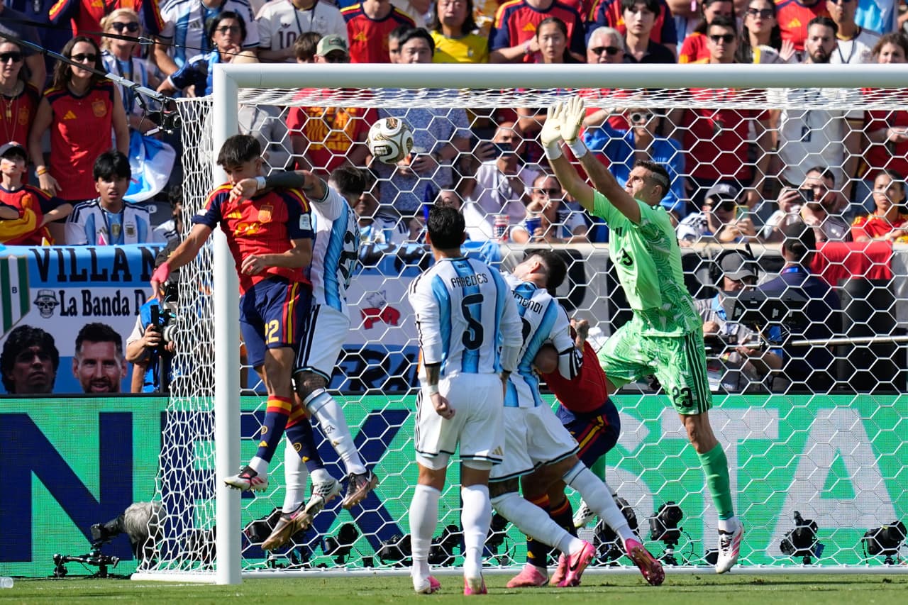 El portero argentino, Dibu Martinez, lucha para mantener el balón fuera del arco en un tiro de esquina.