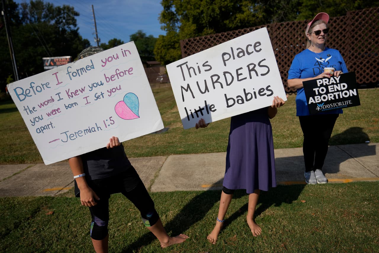 Manifestantes en contra el aborto,
<b> incluidas dos adolescentes</b>, sostienen carteles frente a Hope Medical Group for Women, en Shreveport, Louisiana. Cuando la mayoría de las mujeres ingresaban al estacionamiento de la clínica, fueron recibidas por dos grupos de manifestantes contra el aborto, en su mayoría hombres del este de Texas, que viajan regularmente a Shreveport.