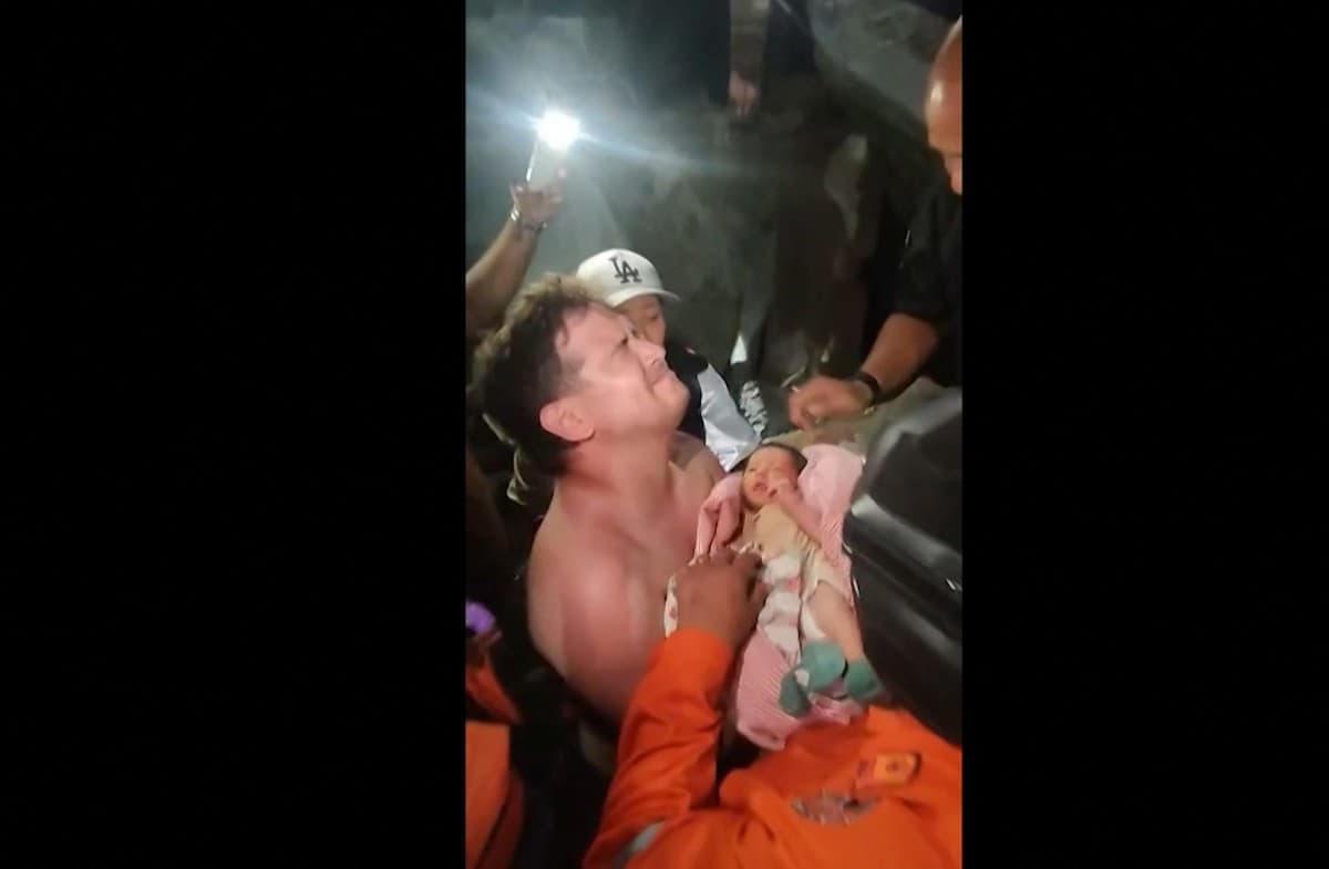 Un hombre sostiene a un recién nacido siendo rescatado con vida de entre los escombros en la ciudad de La Guaira, Venezuela.
