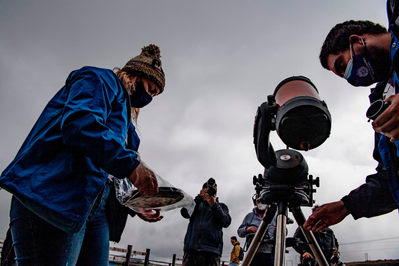 Simon Angel (derecha) y Daniela Fernandez (izquierda), astrónomos de la Universidad Católica de Chile, preparan un telescopio con la finalidad de obervar el eclipse solar, que en la cosmovisión indígena representa "la muerte temporal del Sol".
<br>
<br>El fenómeno se pudo observar desde cualquier altura, aunque especialmente en varios puntos emblemáticos como el Cerro San Cristóbal, una pequeña montaña que se encuentra en una zona céntrica de la capital, y el Cerro Calán, más al oriente, donde opera un observatorio astronómico.