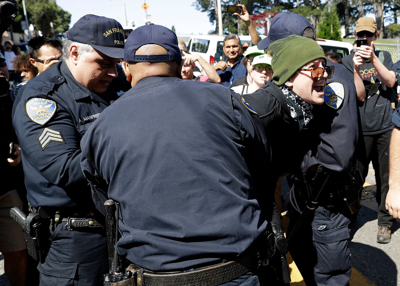 San Francisco Police Officers arrest a protester outside of Alamo Square Park in San Francisco, Saturday, Aug. 26, 2017. San Francisco officials took further steps Saturday to prevent violence ahead of a planned news conference by a right-wing group. Officials erected fencing and a large contingent of police monitored Alamo Square park, where the group Patriot Prayer was set to hold its event. (AP Photo/Marcio Jose Sanchez)