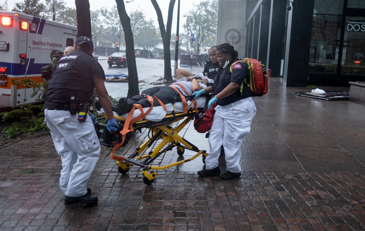 La empresa eléctrica Con Edison dijo que unos 110,000 clientes han sufrido cortes en su suministro dentro de la ciudad, un número de cortes
<b>que solo fue superado por los vividos durante el huracán “Sandy” (2012) y la tormenta tropical “Irene” (2011)</b>,
<a href="https://www.ny1.com/nyc/all-boroughs/weather/2020/08/04/isaias-new-york-city-august-4" target="_blank">según informó el canal local NY1. </a>
<br>
<br>En la imagen, una persona que resultó herida mientras intentaba asegurar barreras es transportada para una revisión médica.