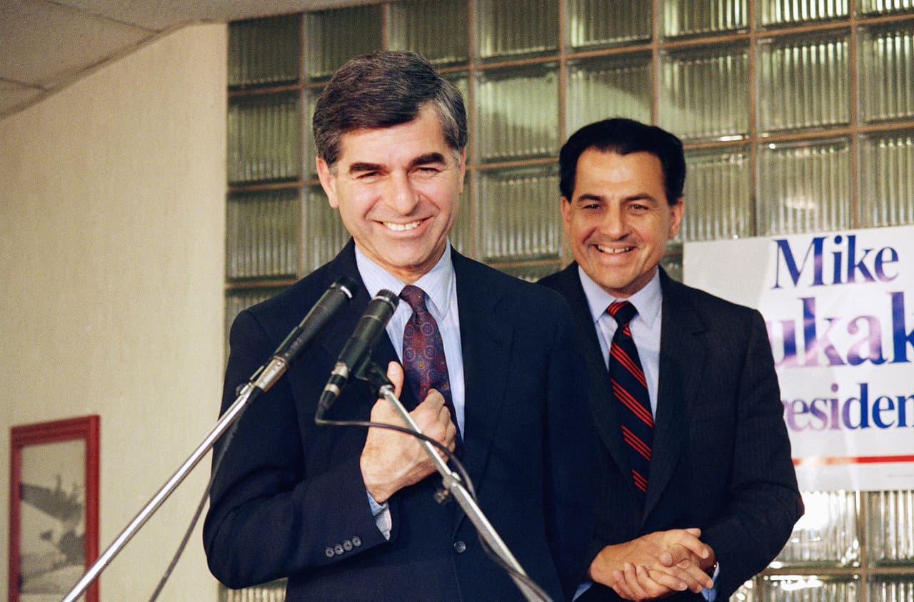 13 de abril de 1988. El gobernador de Massachusetts Michael Dukakis es escoltado por Rafael Hernández Colón, luego de que éste anunciara su endoso como candidato presidencial por el Partido Demócrata durante una conferencia de prensa en el Aeropuerto LaGuardia en Nueva York.
<br>
<br>