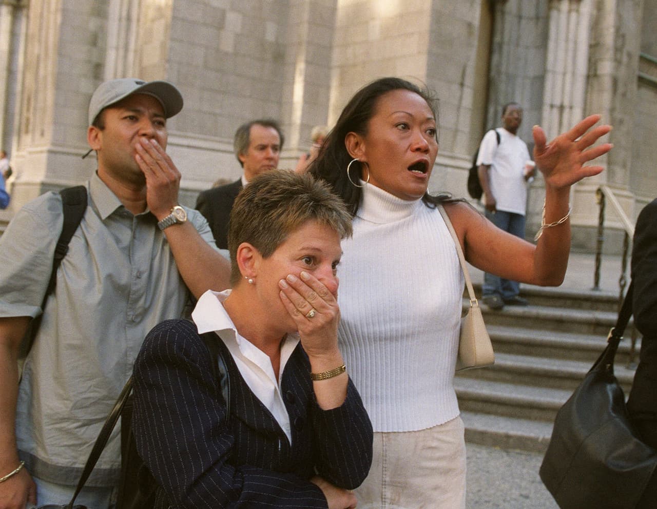 Neoyorquinos frente a la catedral de San Patricio de Nueva York reaccionan impresionados instantes después de que el primer avión chocó contra la Torre Norte del World Trade Center. La primera colisión fue a las 8:46 de la mañana del 11 de septiembre.
