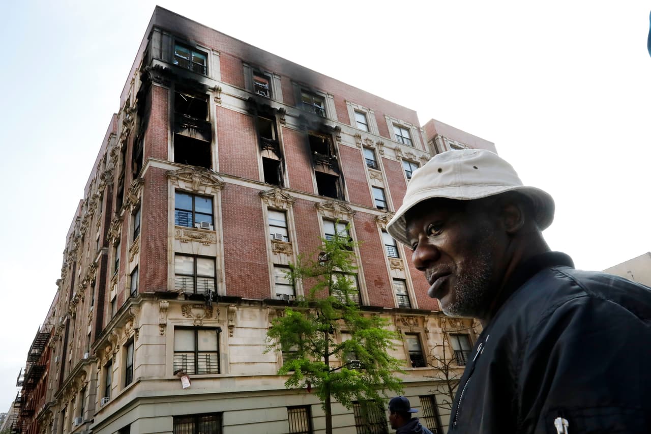Leon Black, residente del edificio incendiado que se ve al fondo. En el incendio murieron seis personas, incluyendo cuatro niños, en Harlem, Nueva York, el miércoles 8 de mayo del 2019. (AP Foto/Richard Drew)