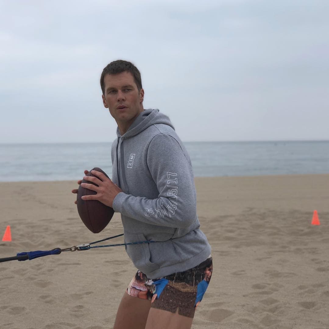 Tom Brady jugando fútbol americano en la playa en la pretemporada 2017.