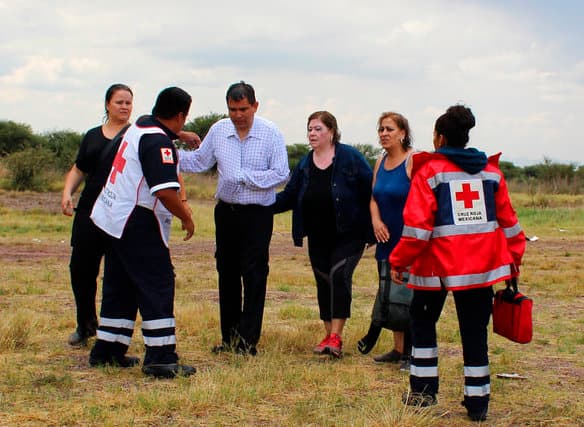 En esta foto distribuida por la Cruz Roja de Durango, socorristas asisten a sobrevivientes de la caída de un avión cuando se alejan del lugar del accidente en un campo cerca del aeropuerto de Durango, México, 31 de julio de 2018. (Cruz Roja Durango via AP)