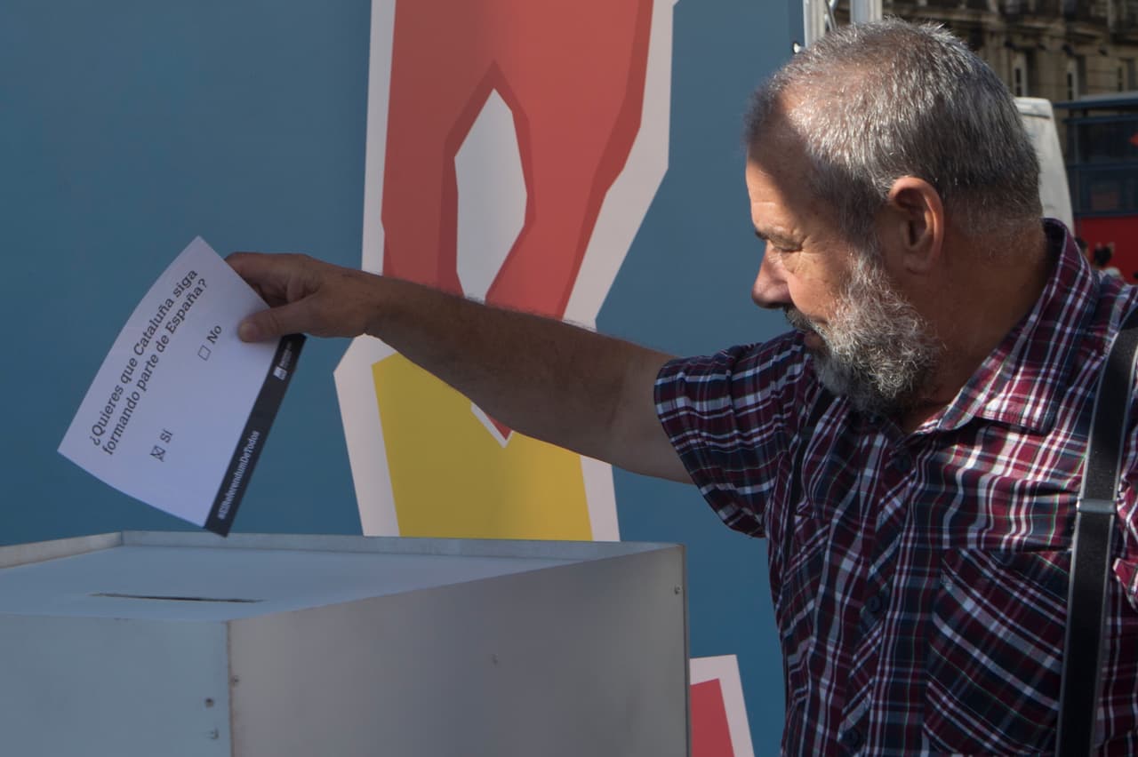 Un hombre deposita una papeleta electoral en un simulacro de votación.