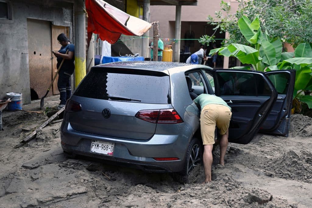 Un hombre limpia su auto que quedó semienterrado en el fango debido a la inundación en Nayarit causada por el huracán Roslyn.