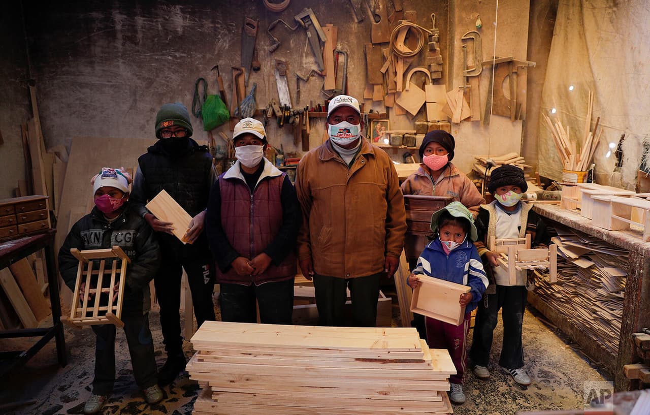 Al igual que en México, la situación en Bolivia tiene a los pequeños de lleno en laborales lejos de las escuelas cerradas. Con máscaras protectoras para frenar la propagación del virus, la familia Delgado posa para una foto en su taller de carpintería en El Alto,
<a href="https://www.univision.com/temas/bolivia">Bolivia</a>.
<b>Después de que el gobierno canceló el año escolar, los cinco niños de entre 6 años y 14 trabajan allí con sus padres. </b>