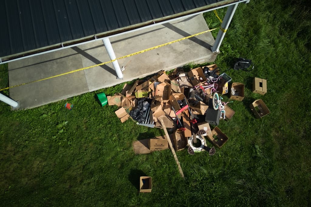 Hay escombros esparcidos en el jardín delantero de una vivienda de donde las autoridades dicen haber retirado a 16 niños y detenido a cuatro adultos en Hamden, Ohio, el miércoles 1 de julio de 2026. (Foto AP/Carolyn Kaster)