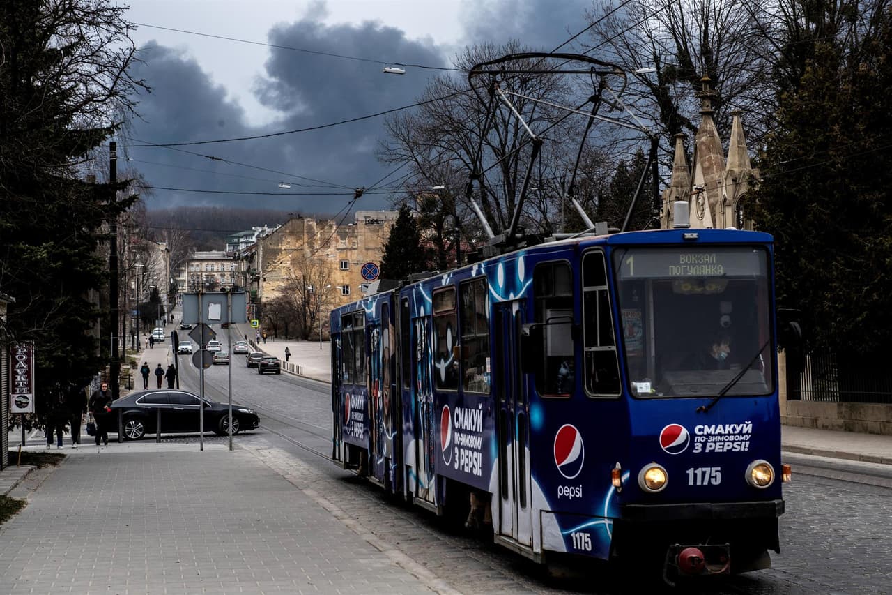 Un tranvía circula por las calles de Leópolis este sábado mientras de fondo se ve el humo negro.
<br>
<br>El gobernador regional, Maxym Kozytsky, dijo en Facebook que
<b>sonaron al menos tres explosiones en las inmediaciones de Leópolis. </b>
<br>