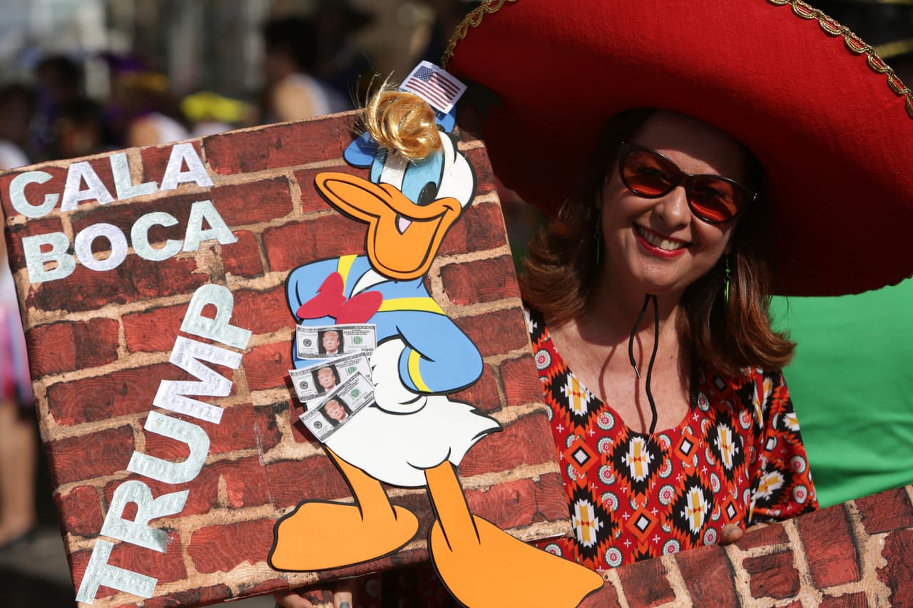 <b>Recife, Brasil. </b>Una mujer lleva un cartel con la figura del pato Donald con cabello rubio que lleva escrito en portugués “Cállate la boca Trump”, en Recife, Brasil. 25 de febrero e 2017.