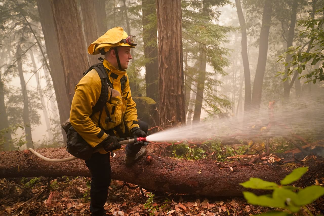 Karol Markowski, miembro del Departamento de Bomberos de South Pasadena,
<b> limpia los puntos calientes mientras lucha contra el incendio del CZU August Lightning Complex</b> en Boulder Creek, California.
<br>