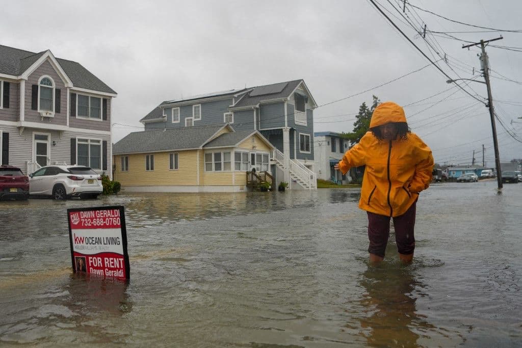 Una mujer camina entre el agua en una carretera inundada durante la tormenta Nor'Easter en una comunidad donde se ha emitido una evacuación voluntaria el 26 de septiembre de 2026 en Point Pleasant, Nueva Jersey.