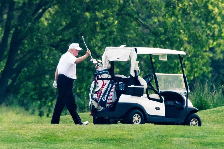El presidente de los Estados Unidos, Donald J. Trump, con un sombrero blanco y una camisa polo blanca, juega al golf en el Trump National Golf Club en Sterling, Virginia, EE. UU., El 23 de mayo de 2020. Es la primera vez que el presidente juega al golf desde el cierre del pandemia de covid-19.