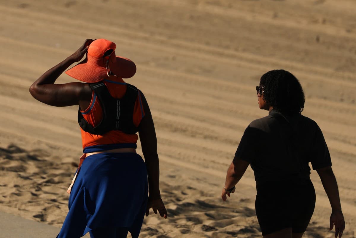 Una persona lleva un sombrero para protegerse del sol matutino mientras camina por The Strand en Redondo Beach, California, durante una ola de calor.