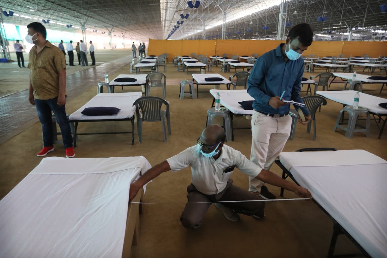 Voluntarios miden que las camas estén a la separación adecuada mientras se preparaban las instalaciones de este hospital de campaña que ya empezó a recibir pacientes en Nueva Deli.