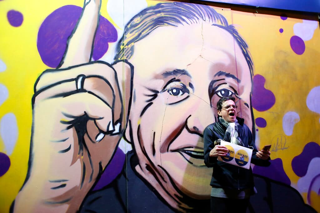 Un partidario de Hernández frente a un mural del candidato, dando un discurso en Bogotá.