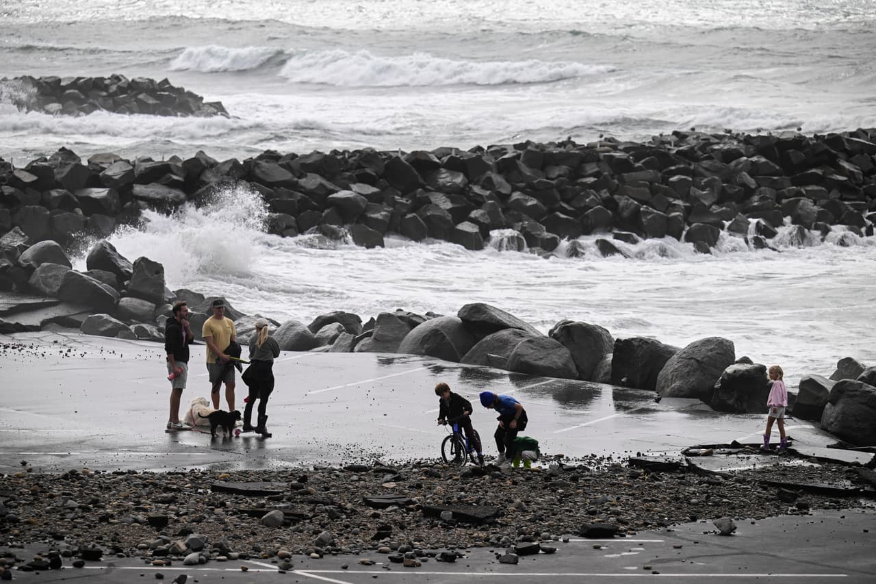 Varias personas caminan por el estacionamiento cerrado de la playa estatal Tamarack en Carlsbad, California, el domingo 11 de octubre de 2026, debido a la tormenta tropical Rachel.