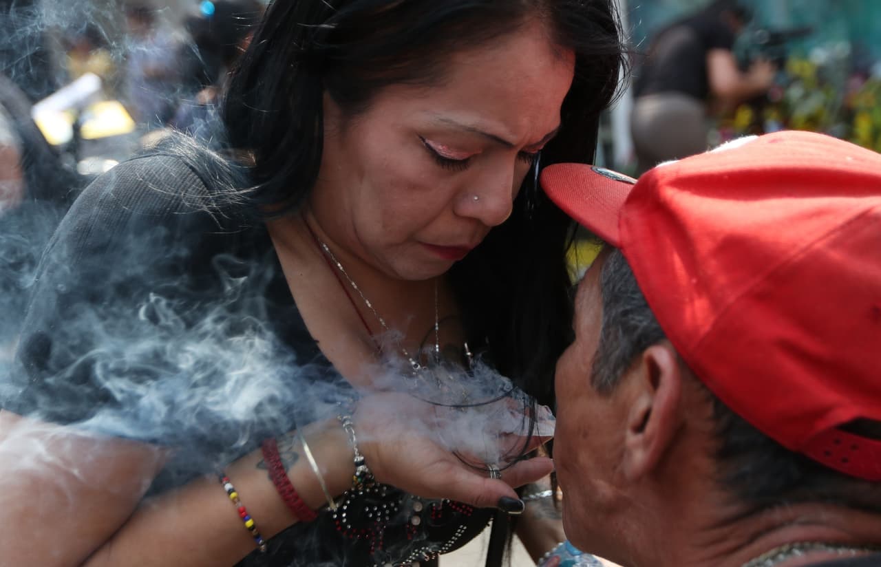 Más allá del porche, en una calle que comprende dos cuadras, varias familias formaron un pasillo en la carretera con ofrendas varias. Había figuritas, dulces, puros y hasta licores sobre las mantas de los vecinos. La mayoría a pie y alguno de rodillas, pero todos los fieles circulaban por ese corredor hacia la vera de la Santa Muerte. Eder, preocupado por el coronavirus, explicó que esta mística figura le ha ayudado con los "problemas de salud de un sobrino" y con "cosas personales, legales" con las que ha tenido que lidiar.