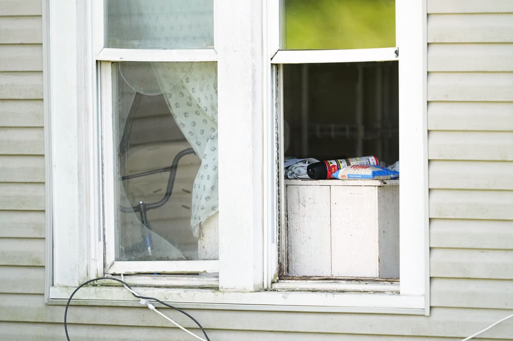 Un saco de arroz y una lata de insecticida se encuentran en la ventana abierta de una vivienda de la que, según las autoridades, fueron retirados 16 niños y detenidos cuatro adultos en Hamden, Ohio, el miércoles 1 de julio de 2026. (Foto AP/Carolyn Kaster)