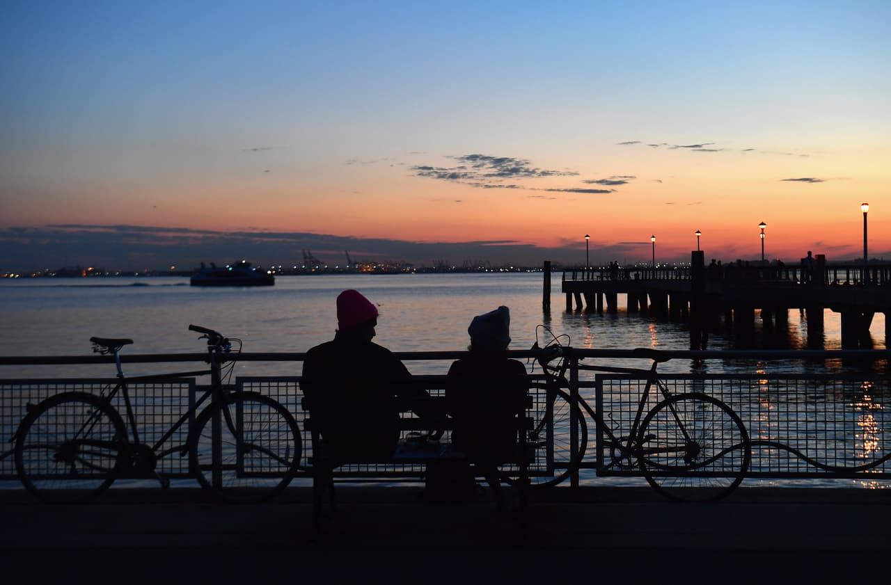 Una pareja observa el atardecer. Han llegado ahí en bicicleta, como puede observarse.