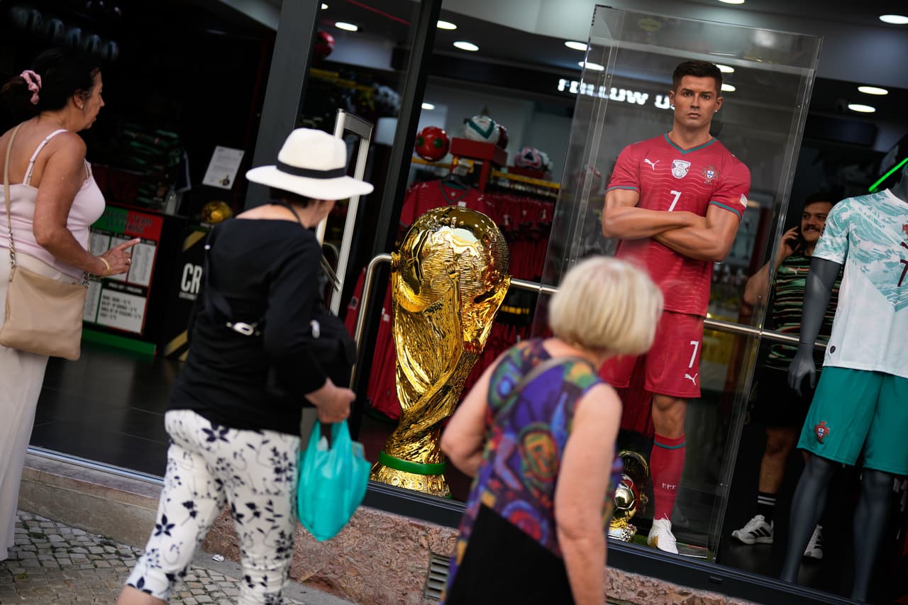 Una réplica del trofeo de la Copa Mundial de la FIFA se exhibe en el escaparate de una tienda junto a un maniquí del capitán de la selección portuguesa de fútbol, Cristiano Ronaldo, mientras los turistas pasean por el centro de Lisboa