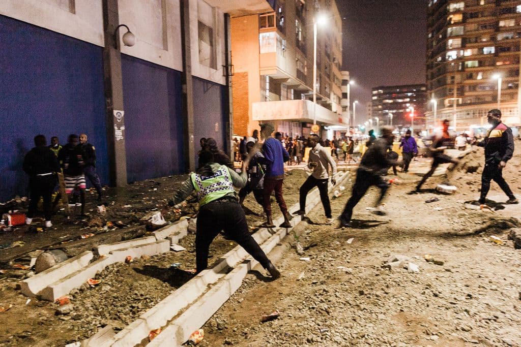Agentes de la policía de Sudáfrica impiden que los saqueadores saqueen en el centro de Durban, el 11 de julio de 2021. Varias tiendas resultaron dañadas y automóviles quemados en Durban, luego de una noche de violencia.