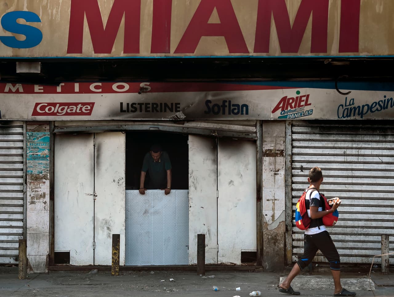 Un viandante pasa por delante de una tienda saqueada y vandalizada durante el apagón que en Maracaibo (Zulia) se extendió por seis días.