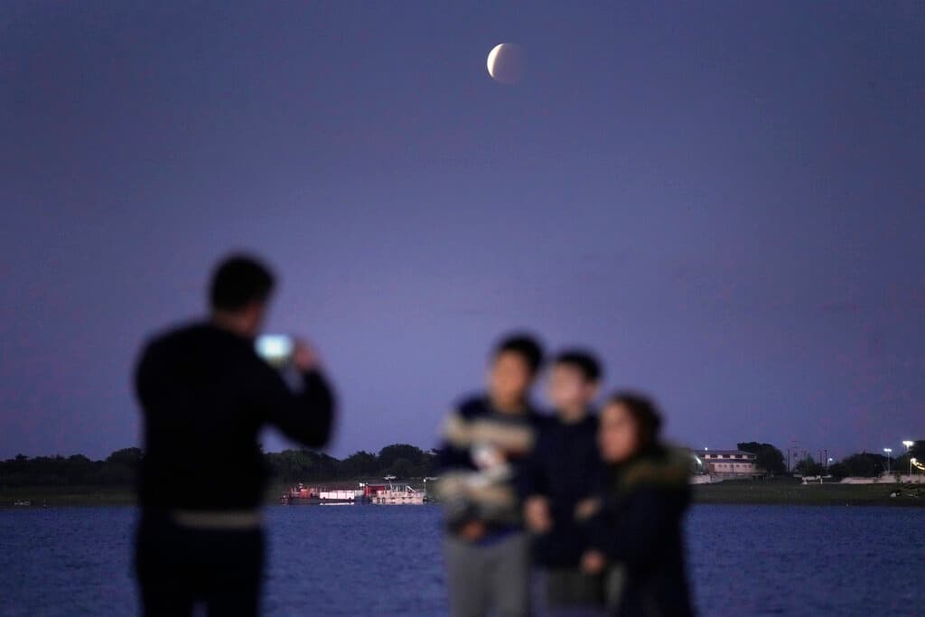 Una familia tomándose una foto con la luna de fondo durante el eclipse en Asunción, capital de Paraguay.