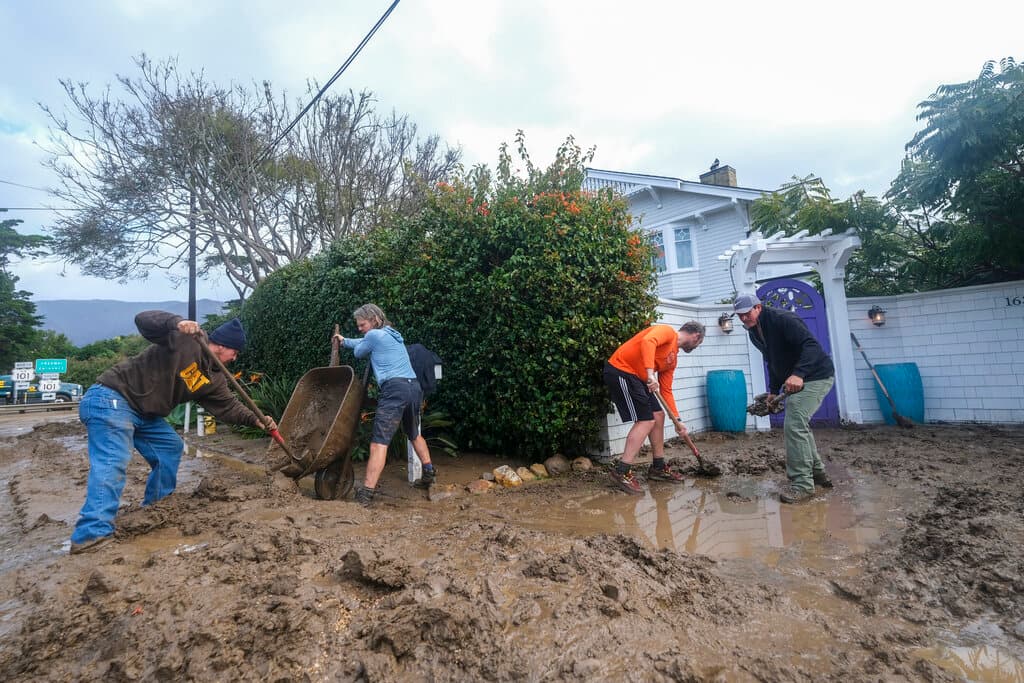 Vecinos de Montecito removiendo los escombros y el lodo que cubrió las calles de un vecindario.