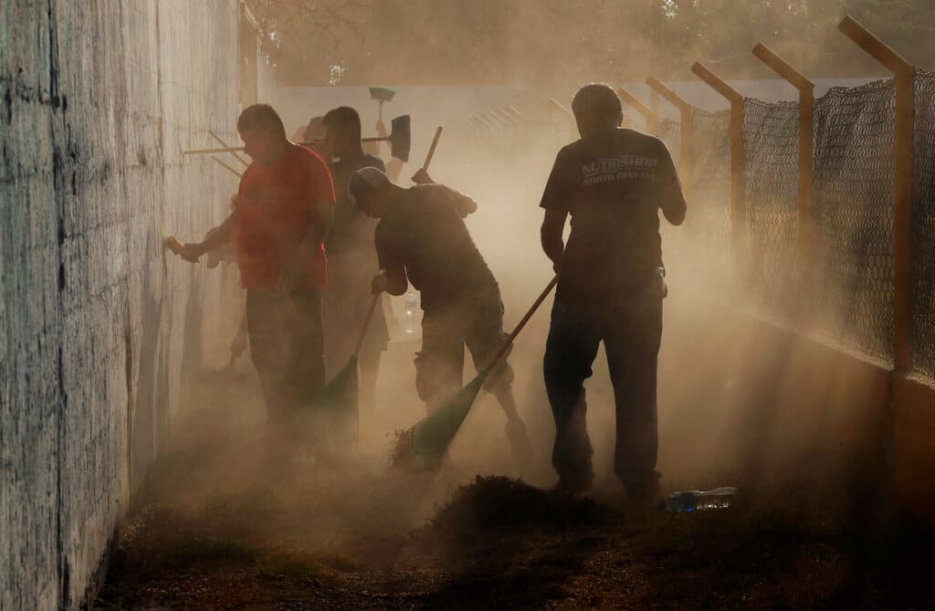 Migrantes centroamericanos que recibieron visas humanitarias de México trabajan a cambio de un salario limpiando un estadio deportivo público, el cual está siendo acondicionado como albergue.
