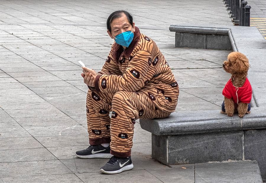 Un hombre protegido con una mascarilla descansa de un paseo con su perro en Wuhan (China), este lunes.