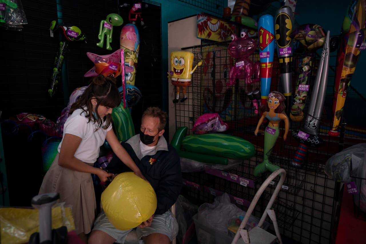 Allan Ansdell Jr. (al centro), propietario del parque temático, infla globos con su hija Abigail poco antes de la apertura del parque, que cerró sus puertas en marzo de 2020 debido a la pandemia.
<br>