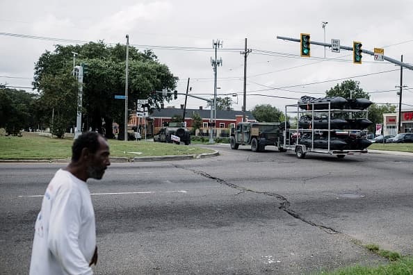 Vecinos de Nueva Orleans ven pasar a los convoy de la Guardia Nacional con los botes que ayudarán en la evacuación.