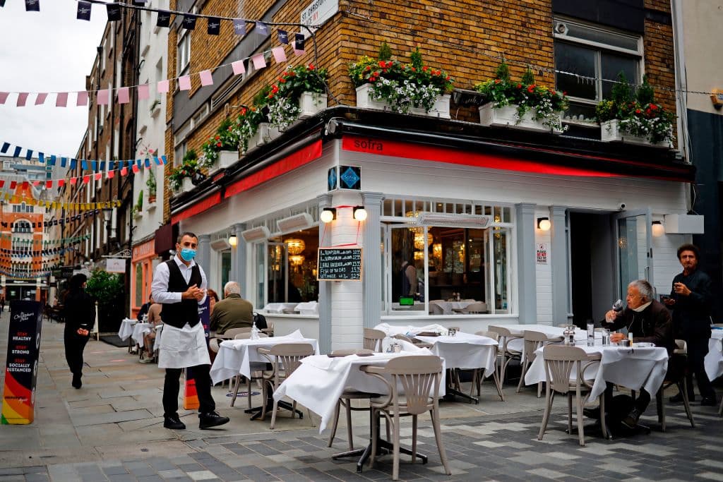 Un camarero con mascarilla atiende las mesas de un restaurante abierto recientemente en el centro de Londres.