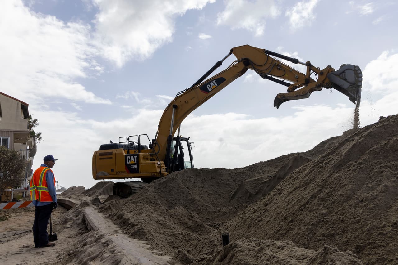 Trabajadores apilan arena en la península de Alamitos, el domingo 11 de octubre de 2026, en Long Beach, California, zona afectada por la tormenta tropical Rachel.
